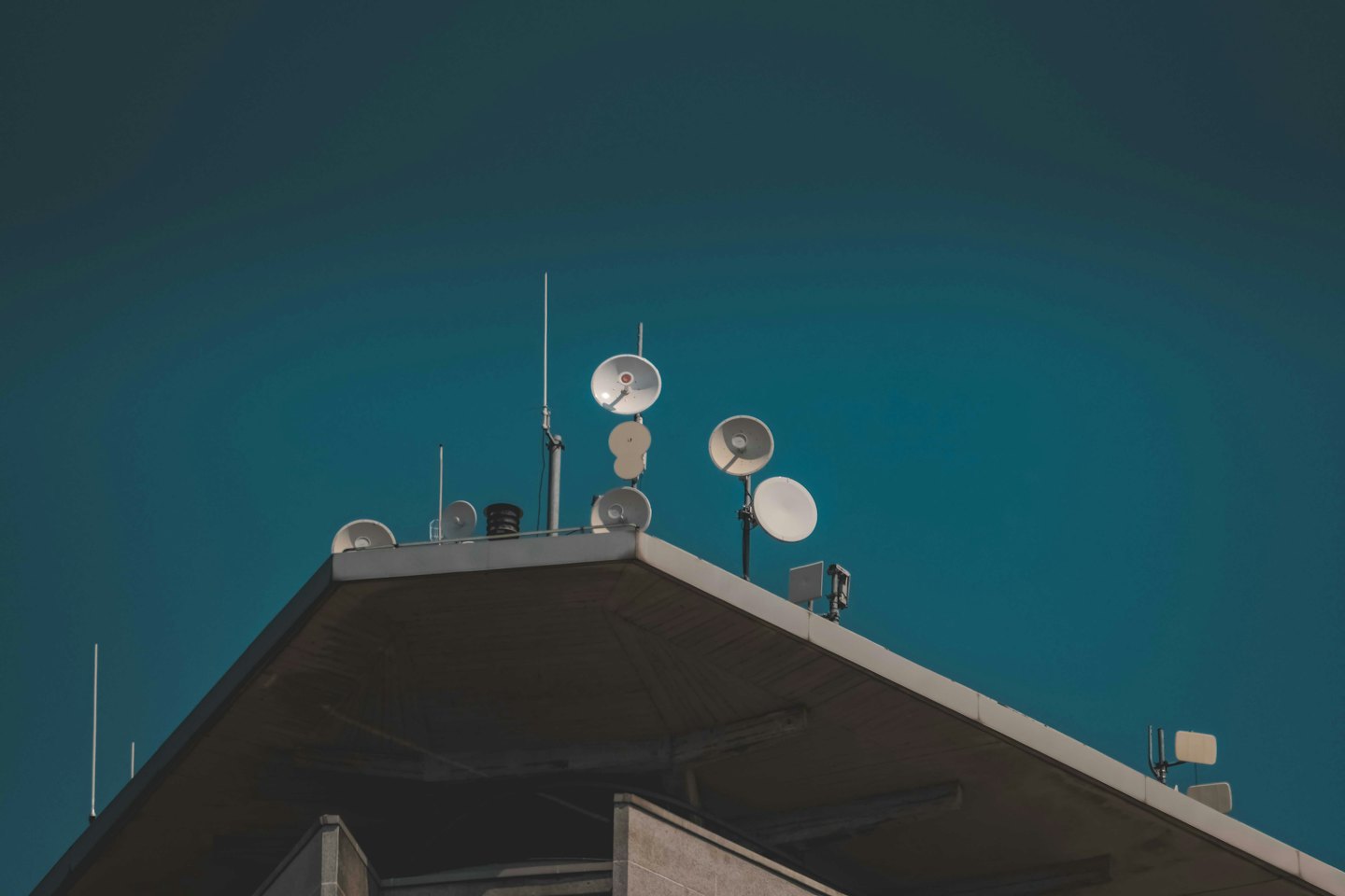 Satellite dishes and communication antennae on a building roof.